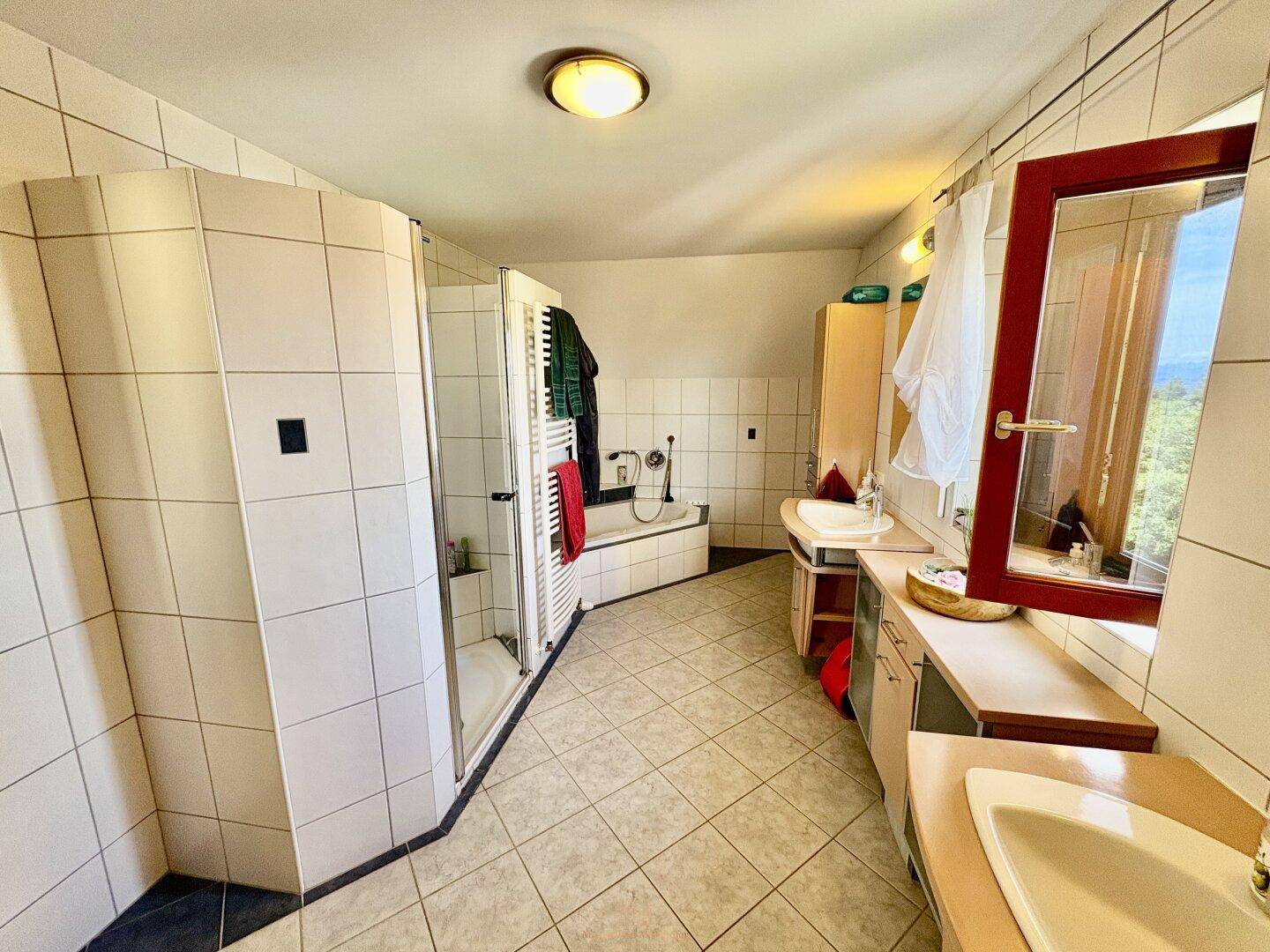 Geräumiges Badezimmer mit Dusche, Badewanne, Doppelwaschbecken und Fenster für Tageslicht.