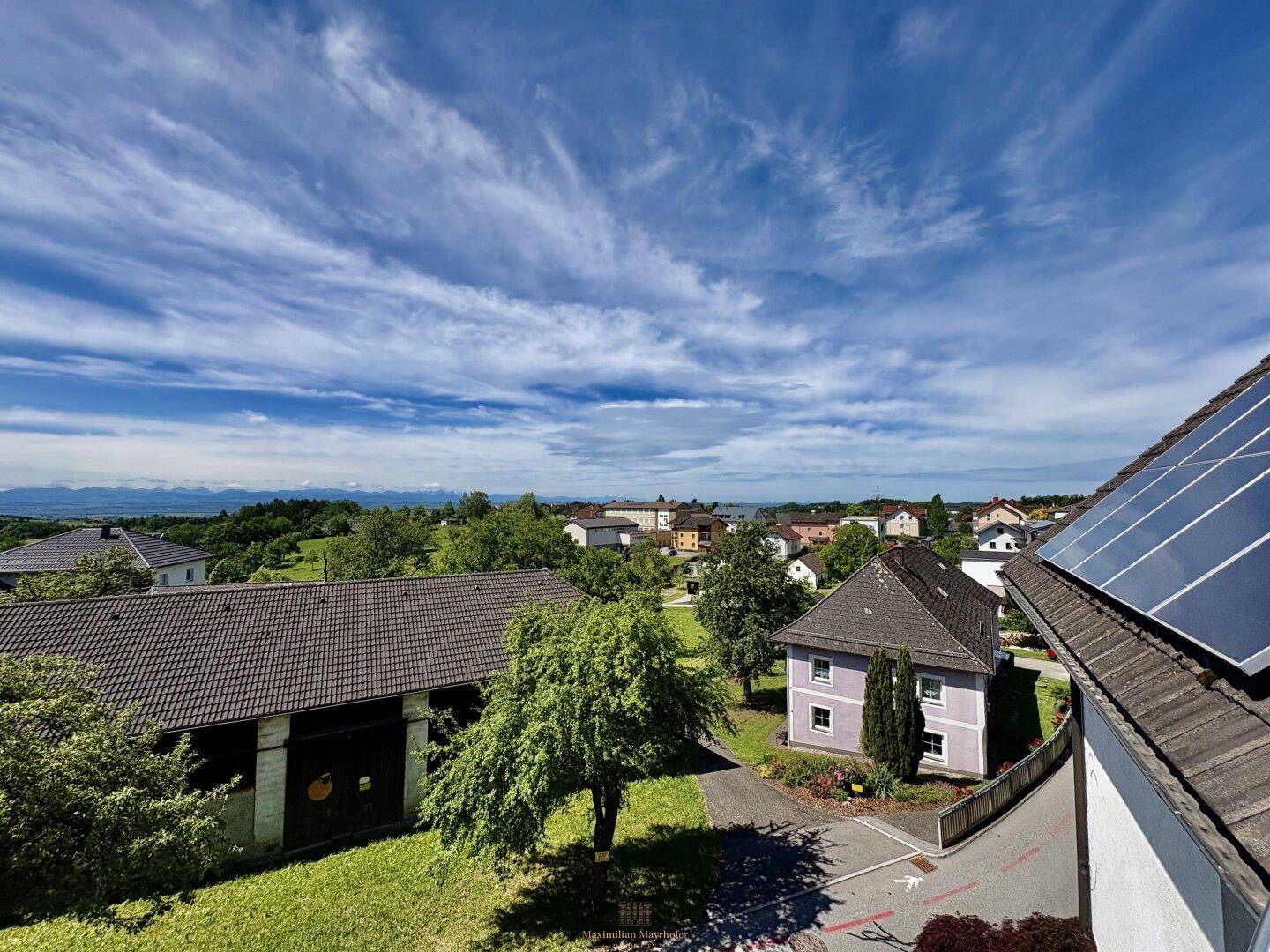 Blick über eine Wohnsiedlung mit Häusern, Bäumen und Solaranlagen auf den Dächern.