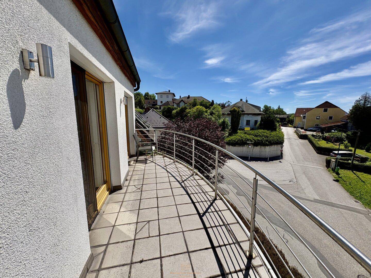 Geschwungener Balkon mit modernem Metallgeländer und Blick auf die Wohngegend.