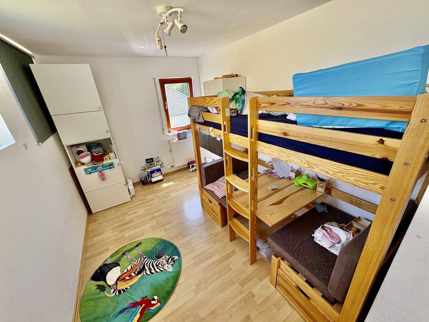 Kinderzimmer mit Etagenbett, Schrank und hellem Holzboden, ideal für Geschwister.