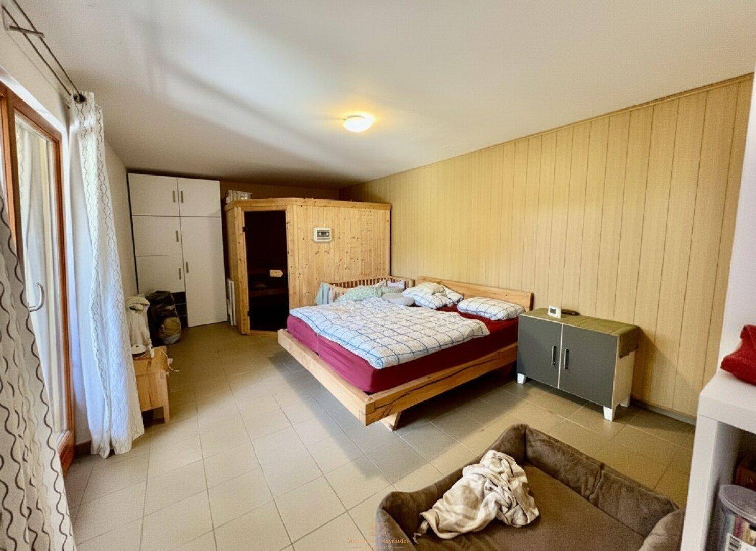 Schlafzimmer mit Holzpaneelen, Fliesenboden und einer integrierten Sauna.