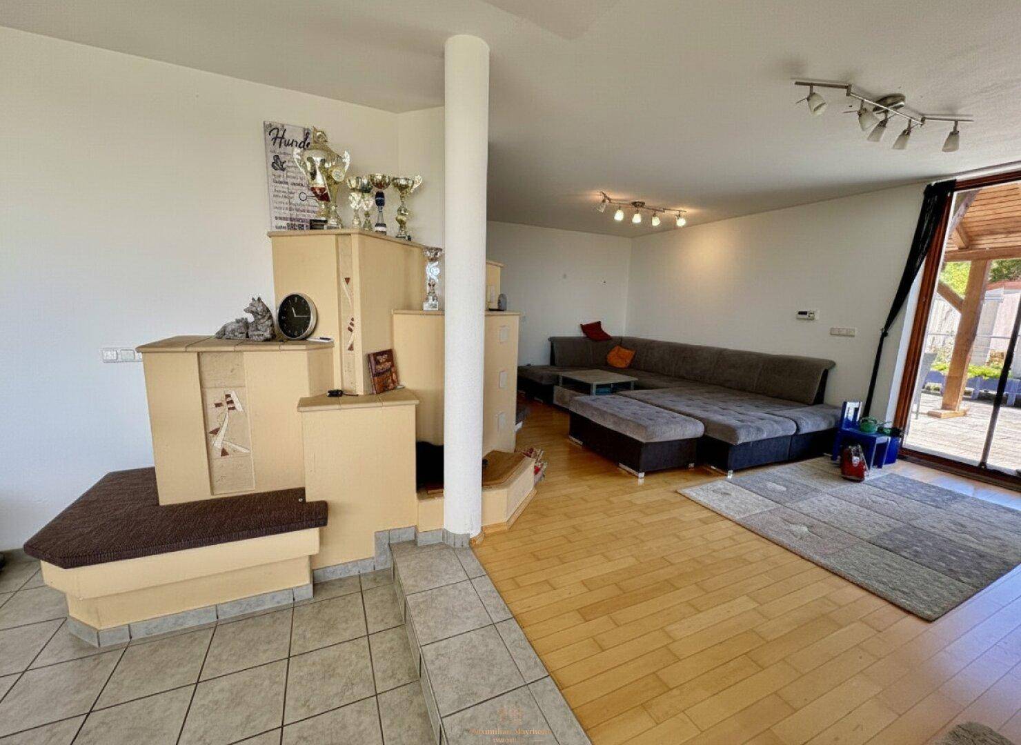 Gemütlicher Wohnbereich mit Sofa, Holzboden und einem Kachelofen.