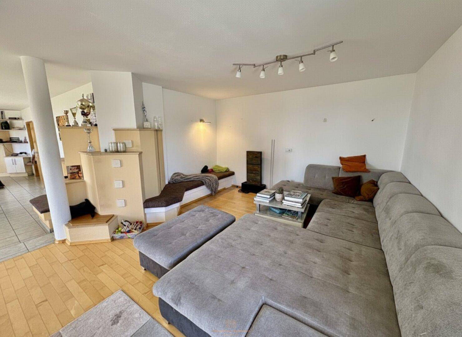 Geräumiges Wohnzimmer mit großem Ecksofa und hellem Parkettboden, offen gestaltet.