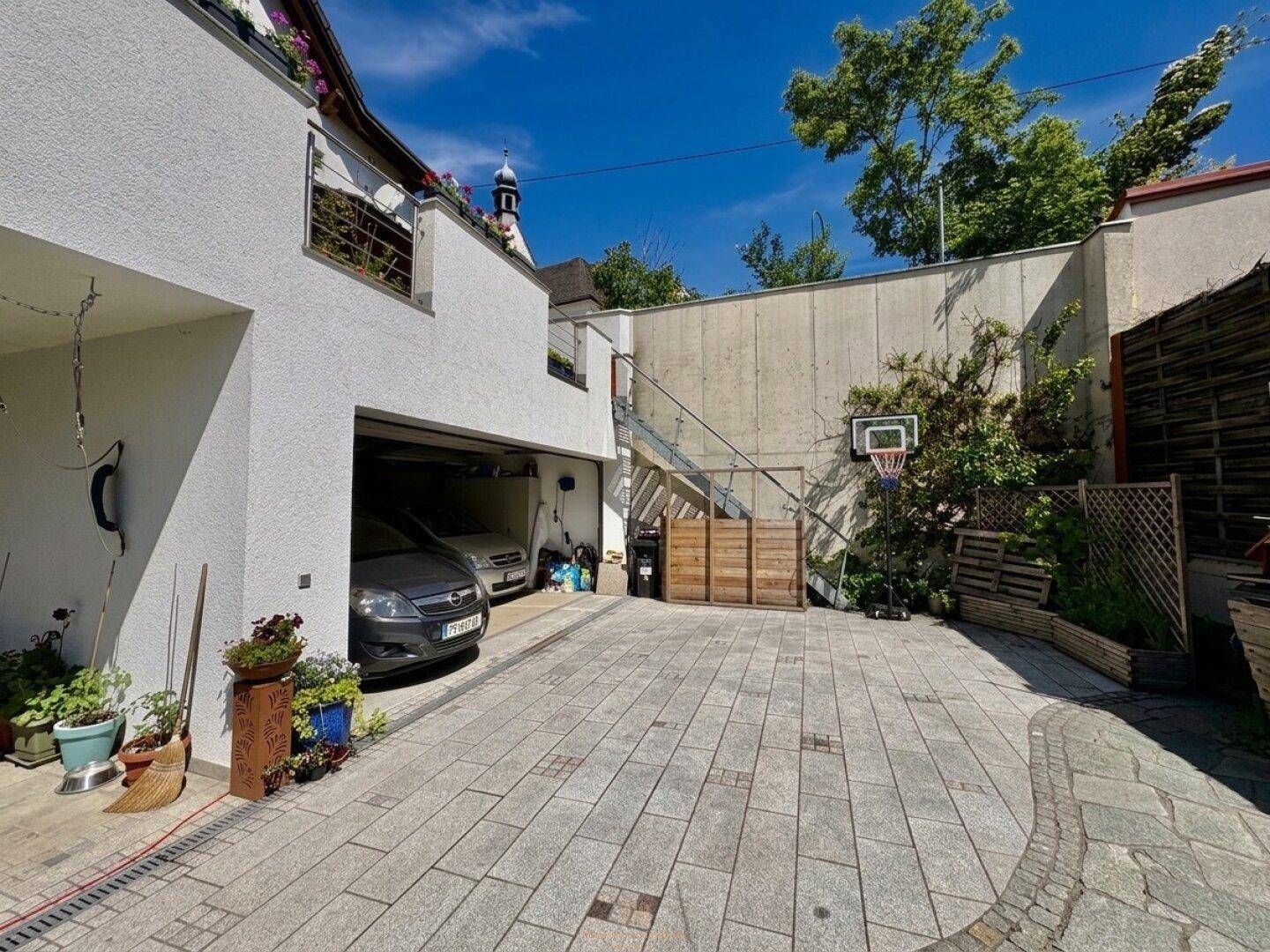 Garage mit gepflastertem Vorplatz und einem Basketballkorb im Freien.