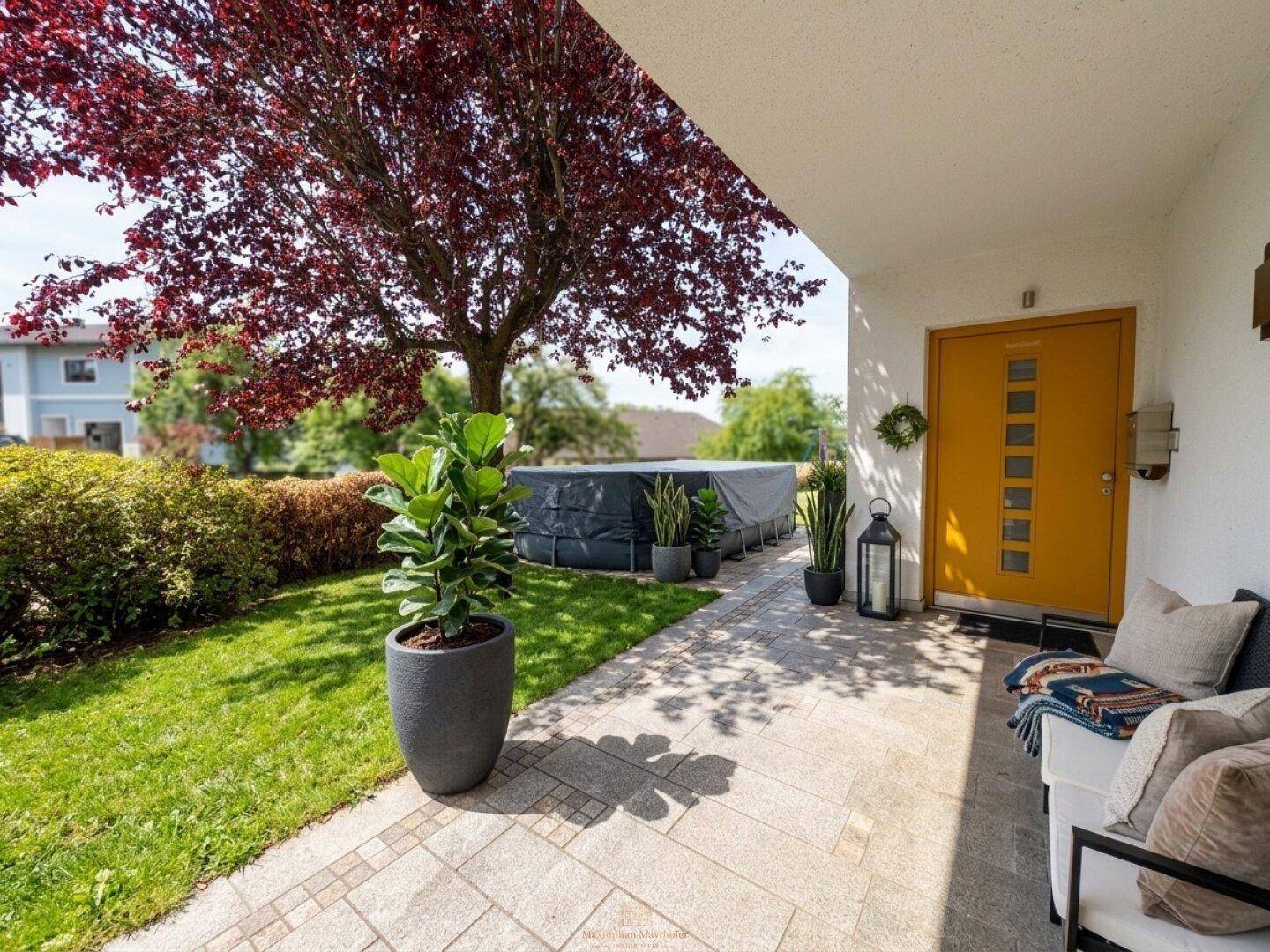 Eingangsbereich mit gelber Tür, Sitzgelegenheit und einem aufgestellten Pool im Garten.
