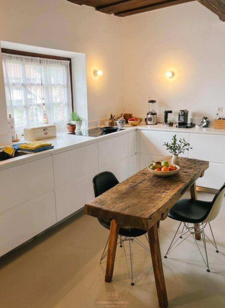 Moderne Küche mit weißen Schränken, Holztisch und Fenster mit Vorhängen.