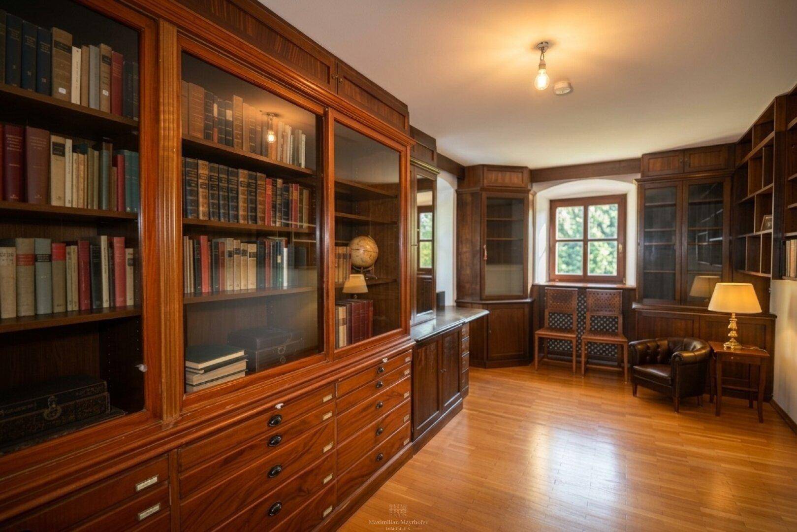 Elegante Bibliothek mit dunklen Holzregalen, gefüllt mit Büchern und klassischer Einrichtung.