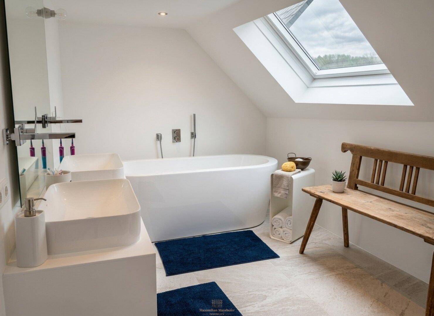 Modernes Badezimmer mit freistehender Badewanne, Doppelwaschbecken und Dachfenster.