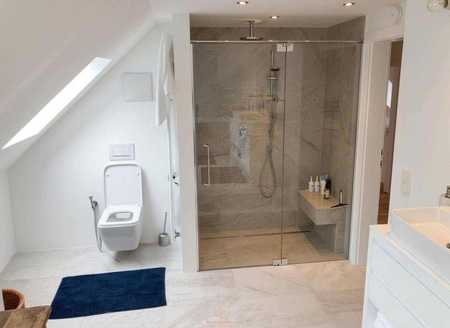 Helles Badezimmer mit begehbarer Dusche, wandmontierter Toilette und Dachschräge.