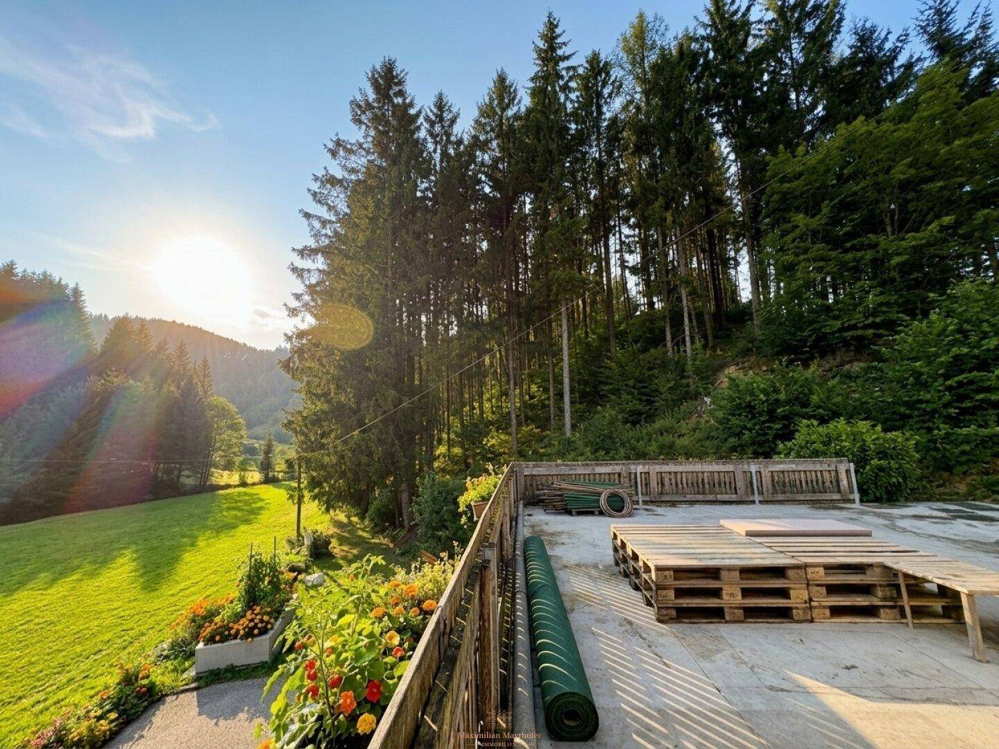 Große Terrasse mit Holzpaletten und Blick auf die umliegende Natur und den Wald.