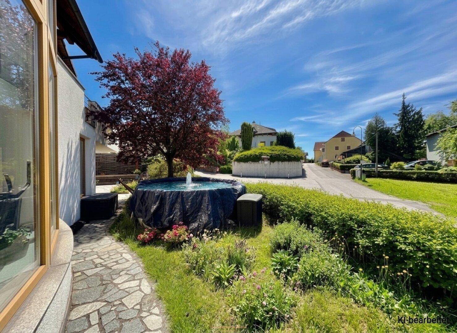 Gepflegter Vorgarten mit Zierbaum, kleinem Teich mit Springbrunnen und gepflastertem Weg.