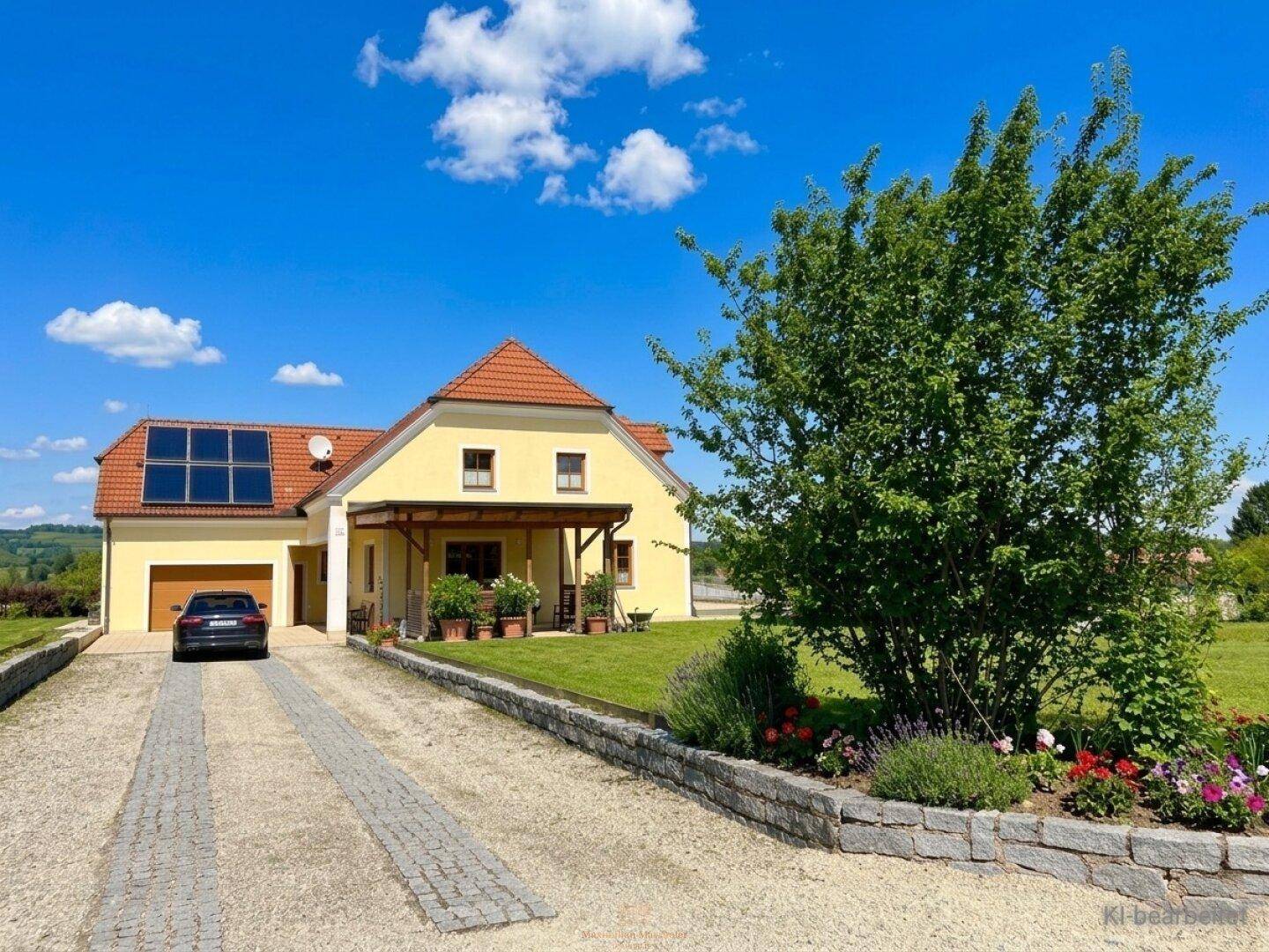 Gelbes Einfamilienhaus mit rotem Dach, Solaranlage und gepflasterter Auffahrt.