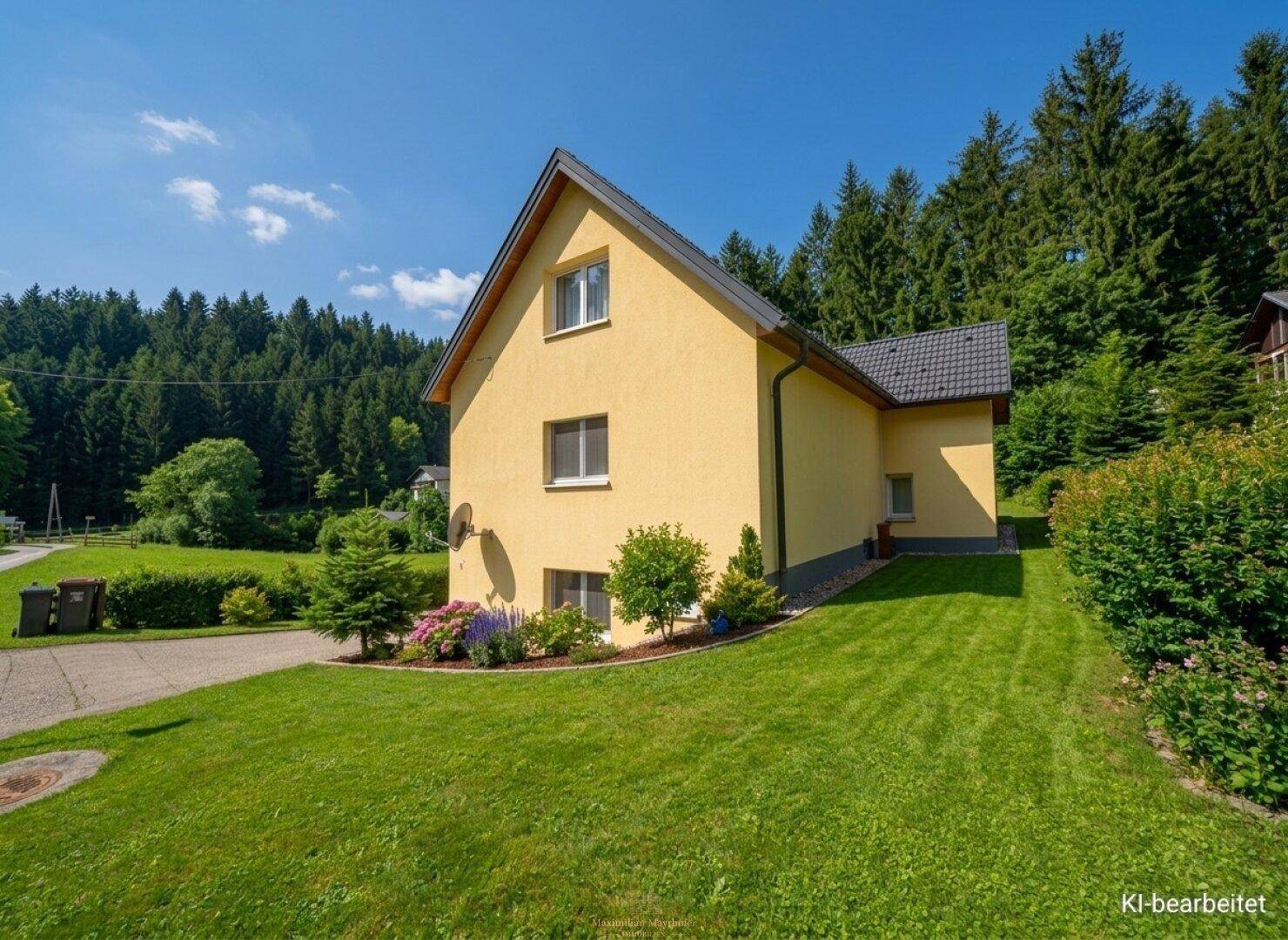 Gelbes Einfamilienhaus mit gepflegtem Rasen und Wald im Hintergrund unter blauem Himmel.