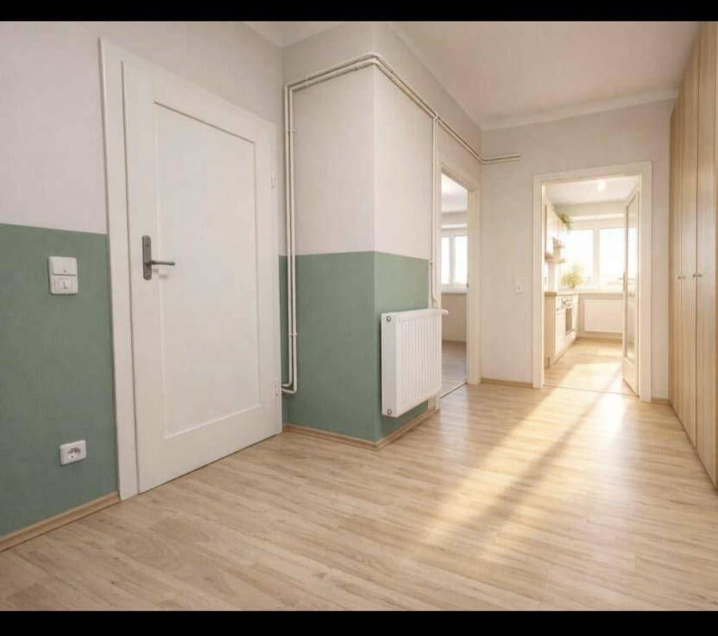 Heller Flur mit Laminatboden, weiß gestrichenen Wänden und Zugang zu weiteren Räumen.