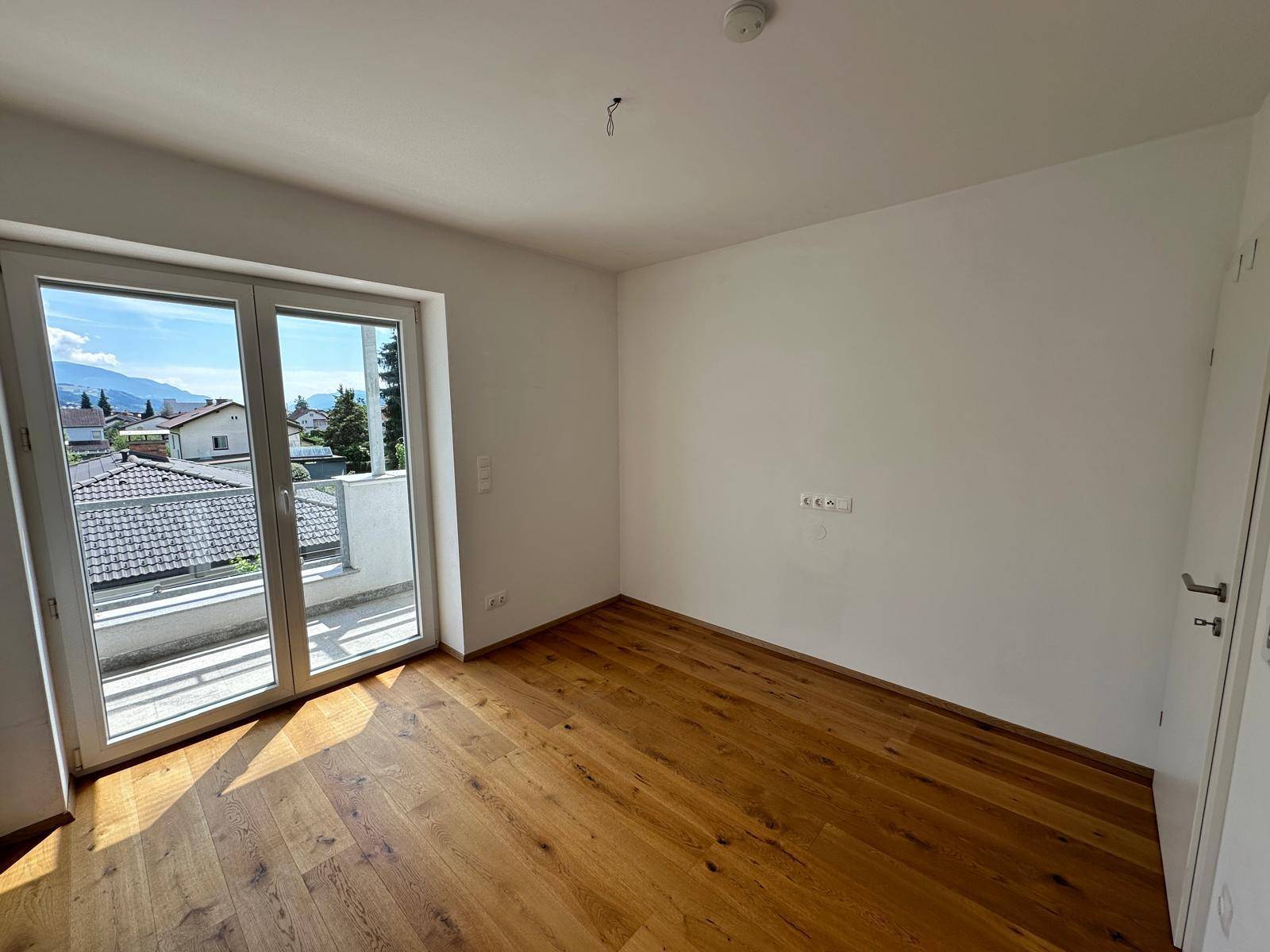 Helles Schlafzimmer mit Holzboden und Zugang zu einem Balkon, bietet einen schönen Ausblick.