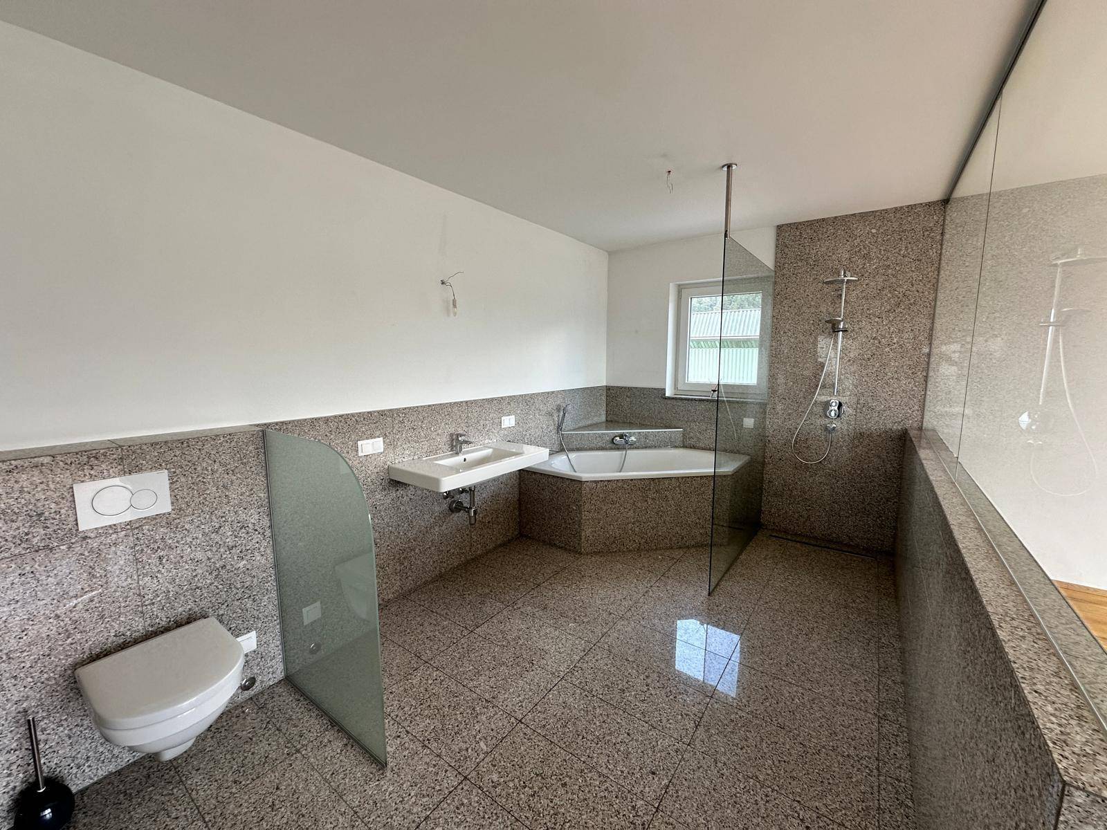 Helles Badezimmer mit Eckbadewanne, wandhängendem WC und modernem Waschbecken auf Fliesenboden.