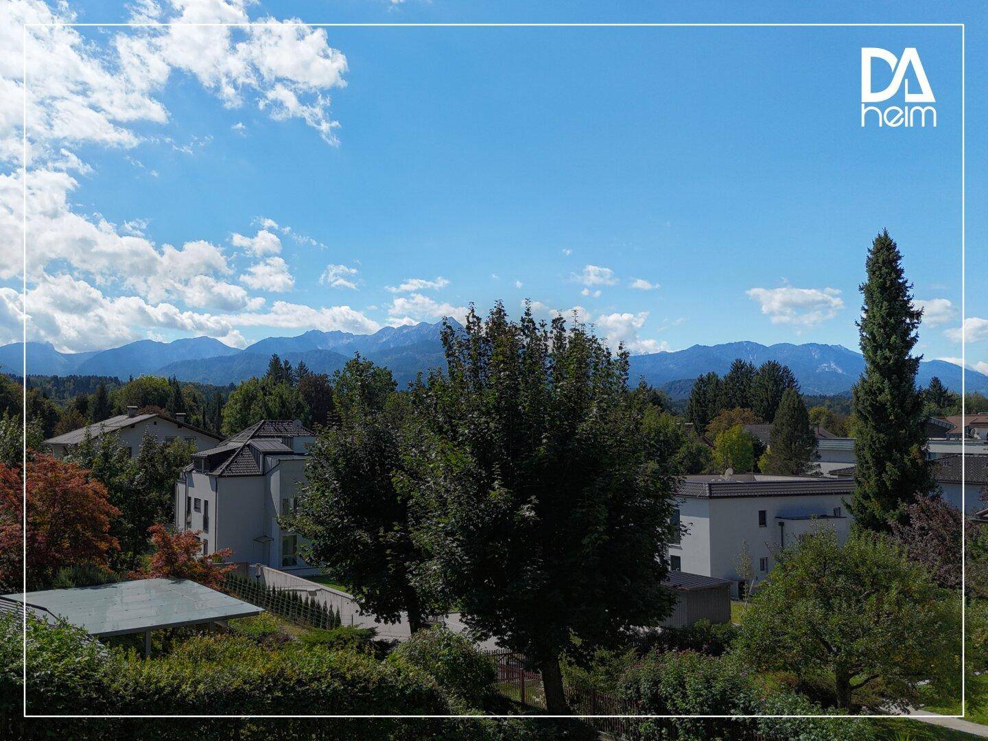 Panoramablick auf die umliegende Landschaft mit Bergen und grünen Bäumen unter blauem Himmel.