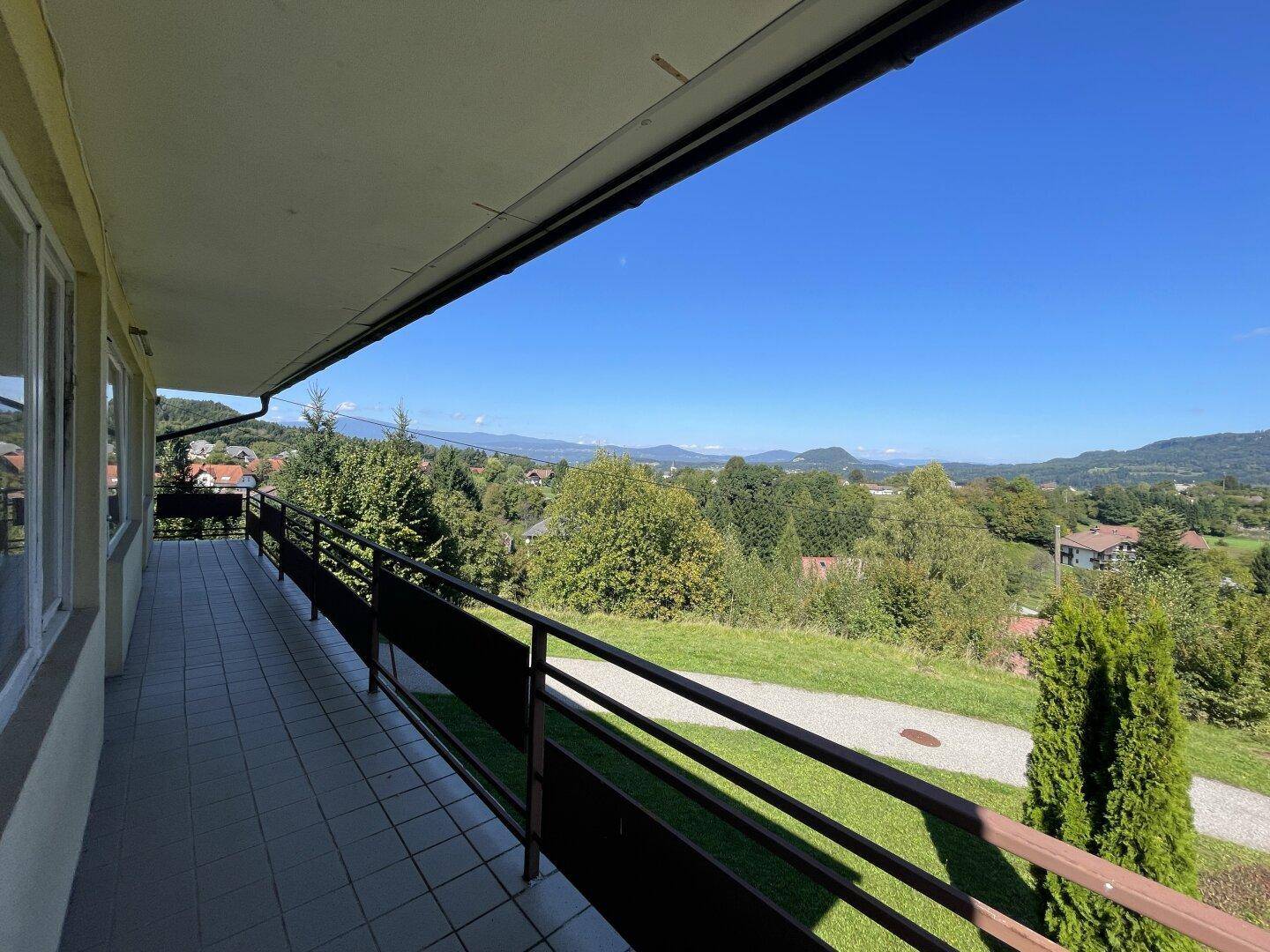 Langer Balkon mit Fliesenboden und weitem Panoramablick über die grüne Landschaft.