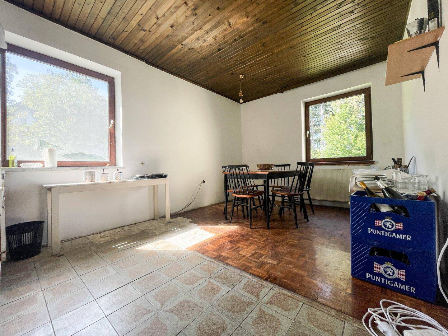 Essbereich mit Holztisch, Stühlen und einer Kombination aus Fliesen- und Parkettboden.