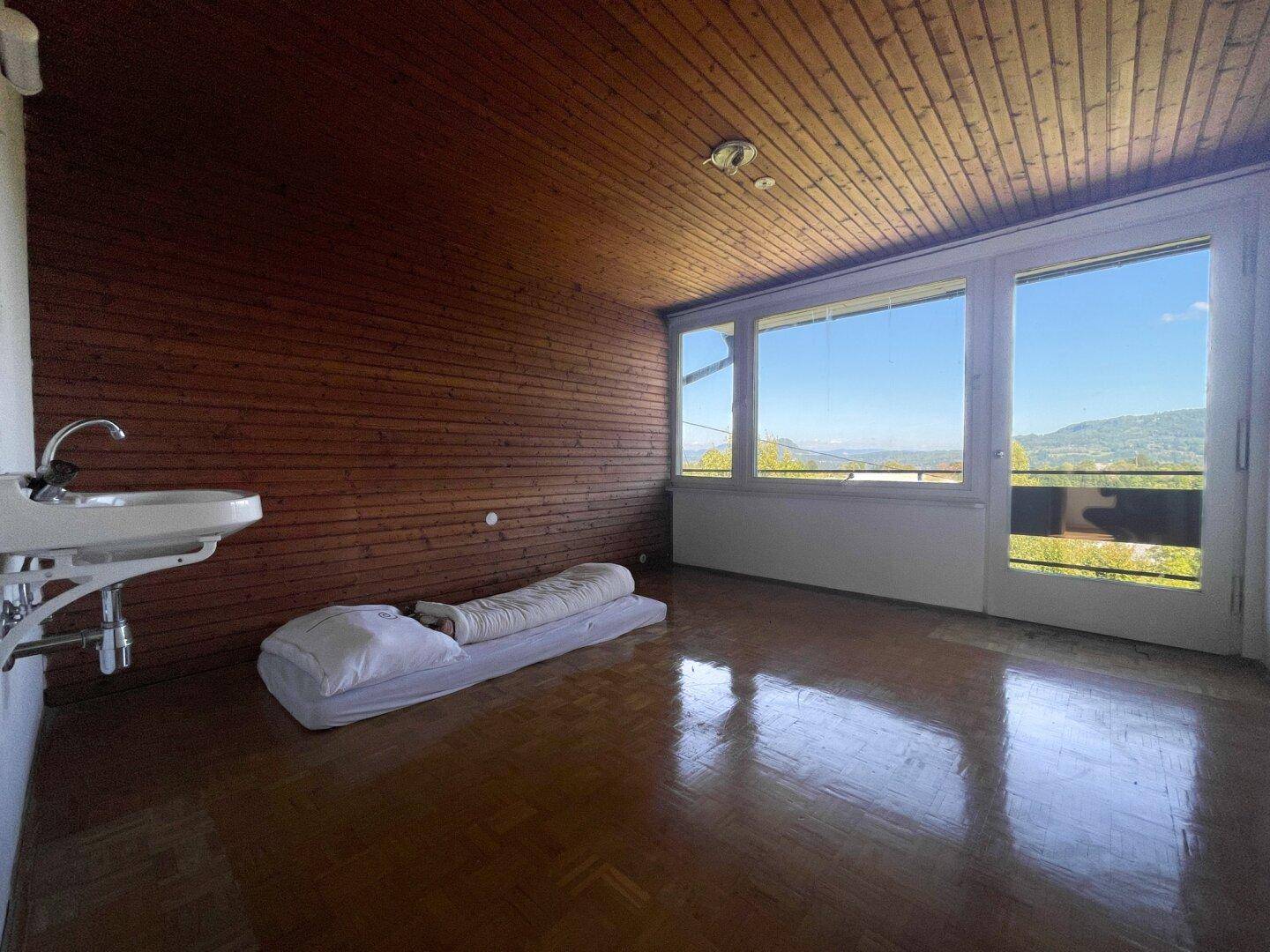 Schlafzimmer mit Holzvertäfelung, Waschbecken und Zugang zu einem Balkon mit Weitblick.
