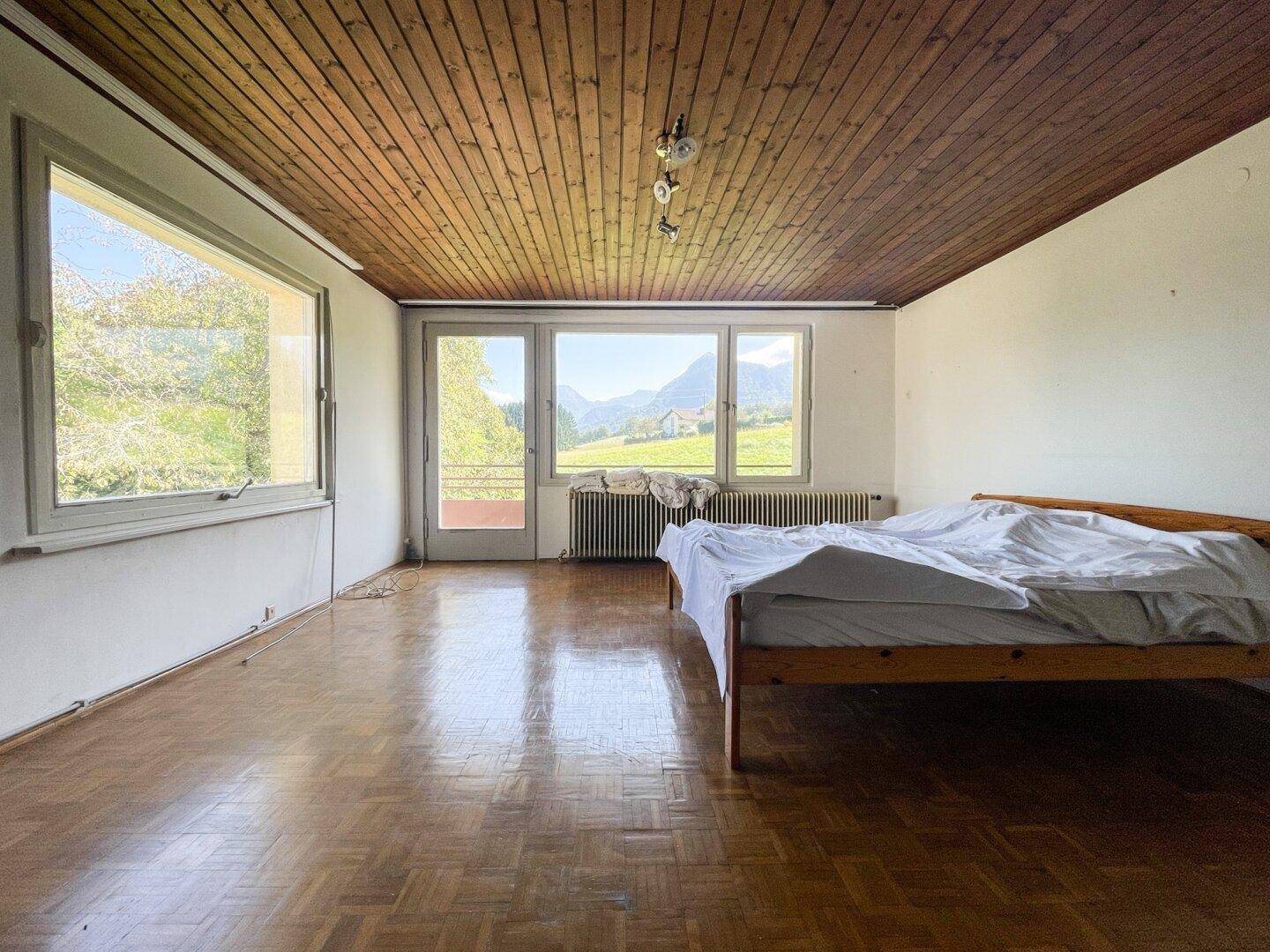 Schlafzimmer mit Holzbalkendecke, Parkettboden und direktem Blick auf die Berge.