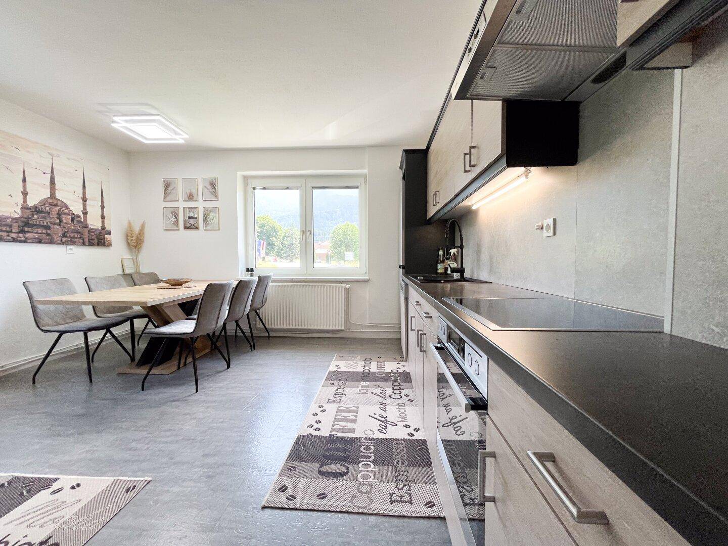 Geräumige Wohnküche mit Essbereich, modernen Geräten und Blick ins Grüne.