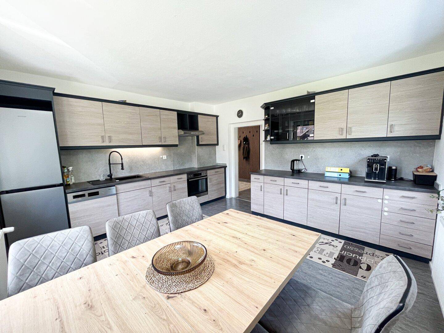 Moderne Einbauküche mit Essbereich, hellen Holzfronten und integrierten Geräten.