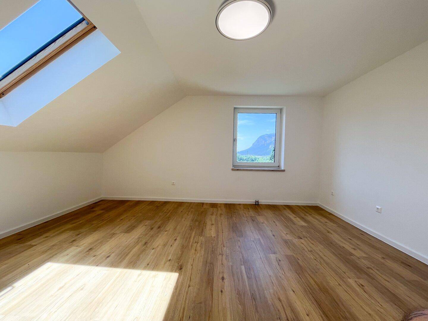 Geräumiges Schlafzimmer im Dachgeschoss mit Fenster und Laminatboden.