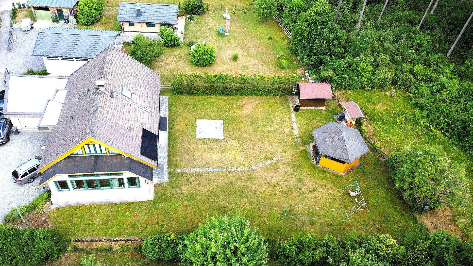 Luftaufnahme des Anwesens mit großem Garten, Nebengebäuden und umgebender Natur.