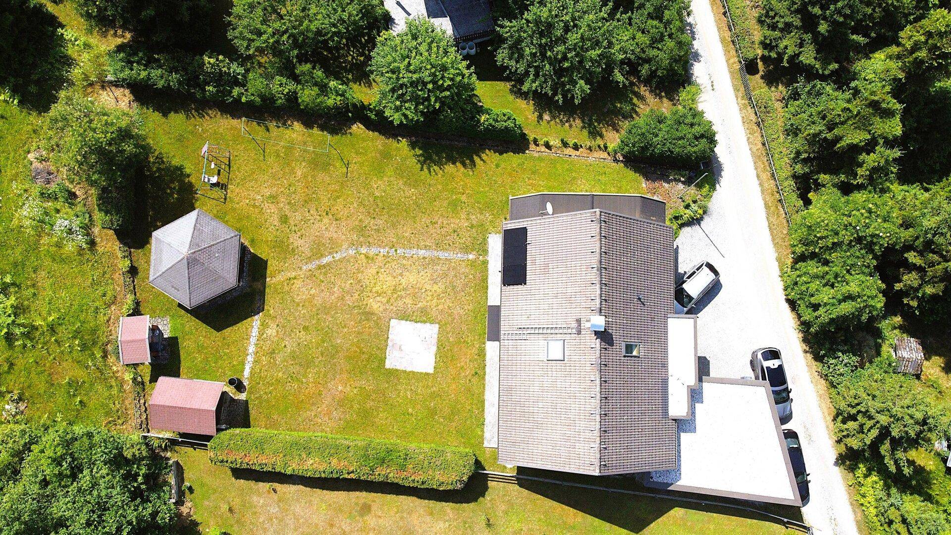 Vogelperspektive des Hauses mit weitläufigem Garten, Nebengebäuden und angrenzendem Wald.