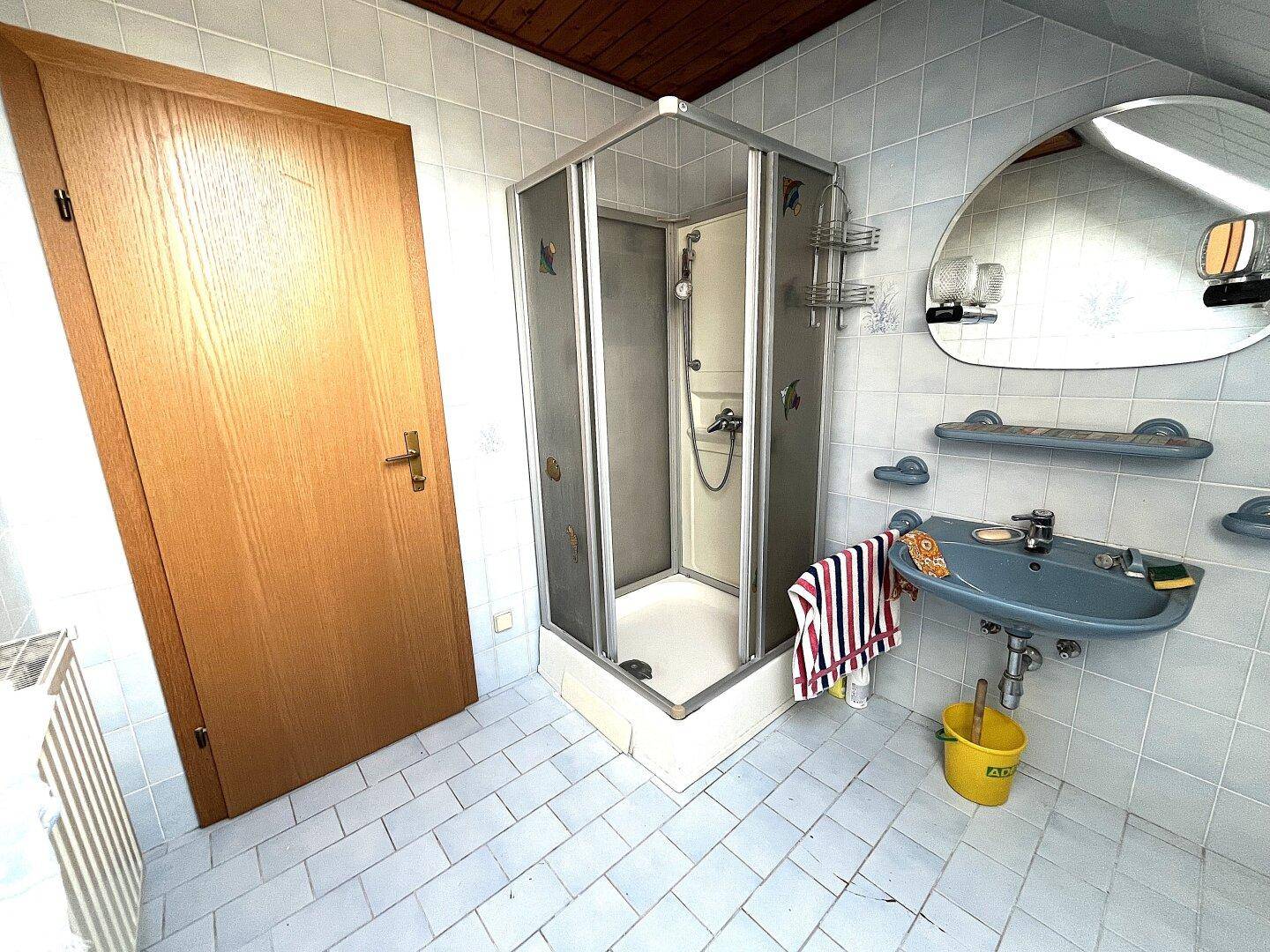 Kleines Badezimmer mit Duschkabine, hellblauen Fliesen und Fenster.