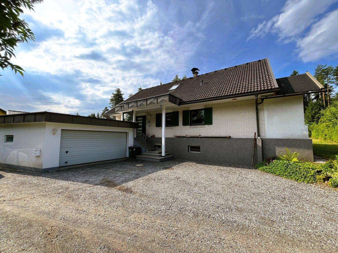 Einfamilienhaus mit integrierter Garage, Kiesauffahrt und gepflegtem Vorgarten.