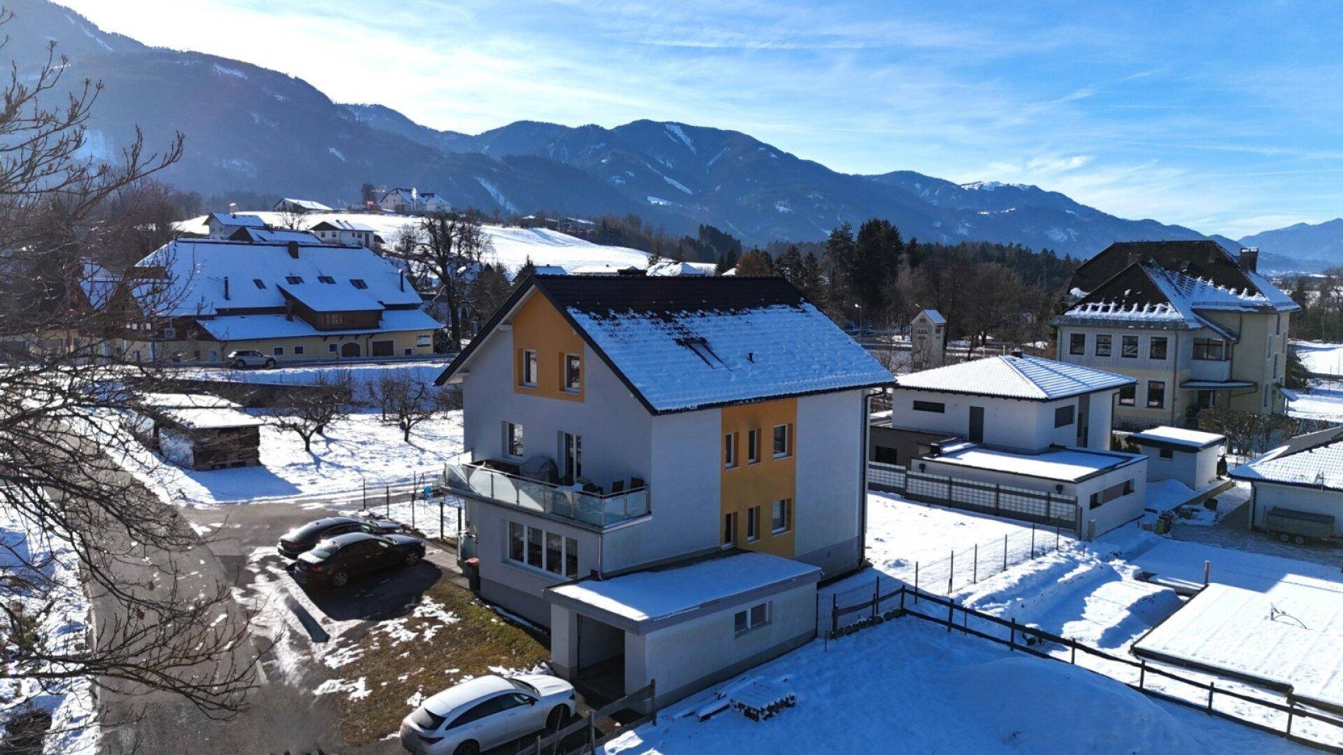 Freistehendes Haus mit Balkon und Bergblick in einer verschneiten Wohngegend.