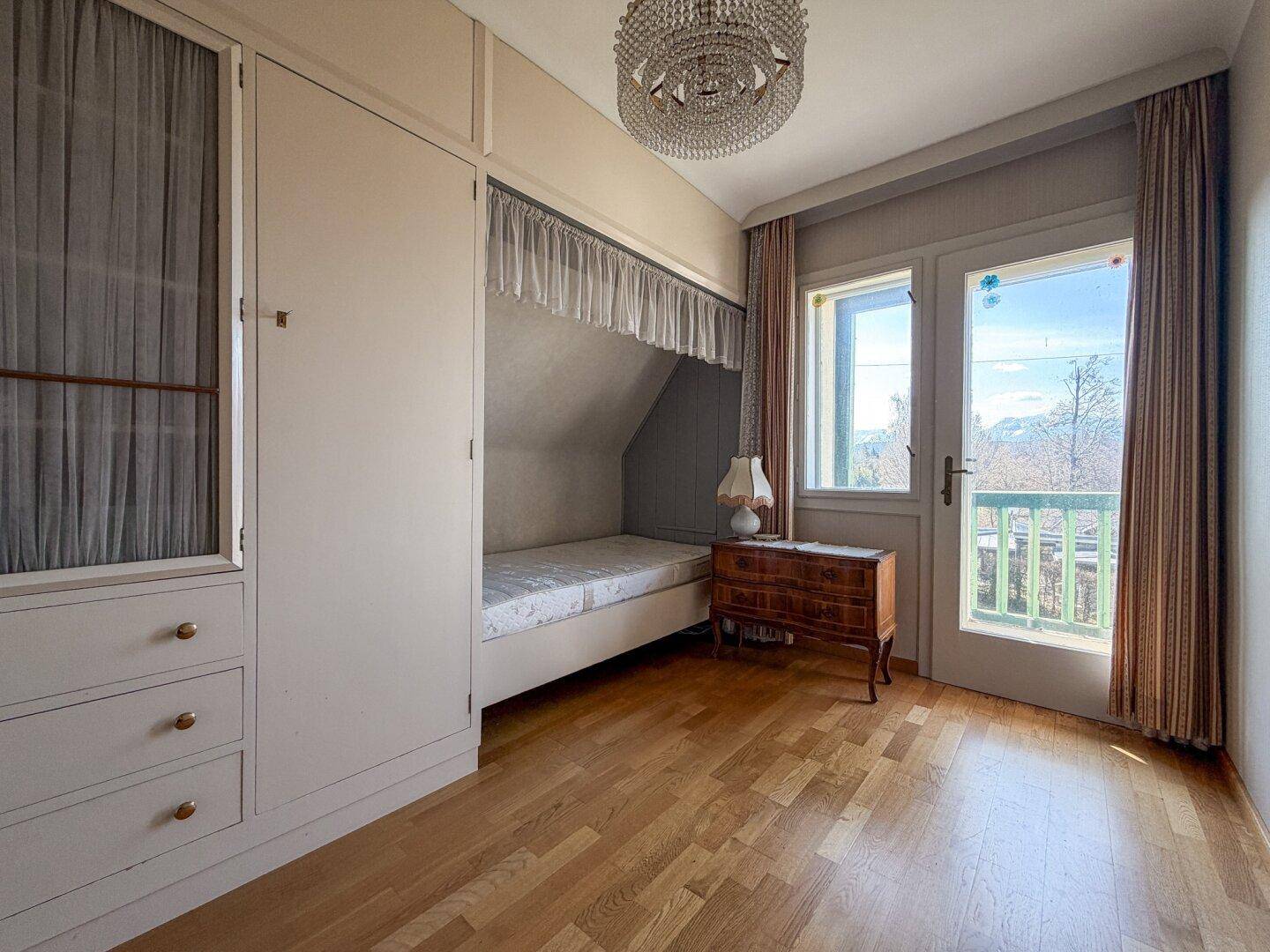 Schlafzimmer mit Einbauschrank, integriertem Bett und Zugang zu einem kleinen Balkon.