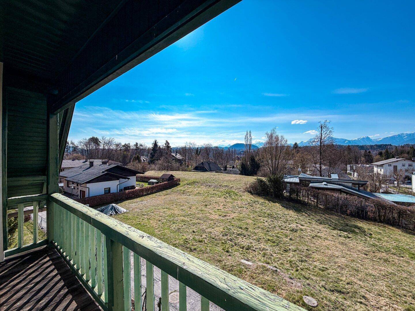 Balkon mit weitem Blick über eine Wiese und die umliegende Landschaft mit Bergen in der Ferne.