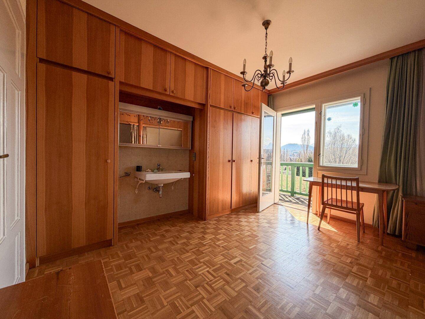 Geräumiges Schlafzimmer mit Holzeinbauschränken, Waschbecken und Balkonzugang, gut gepflegt.