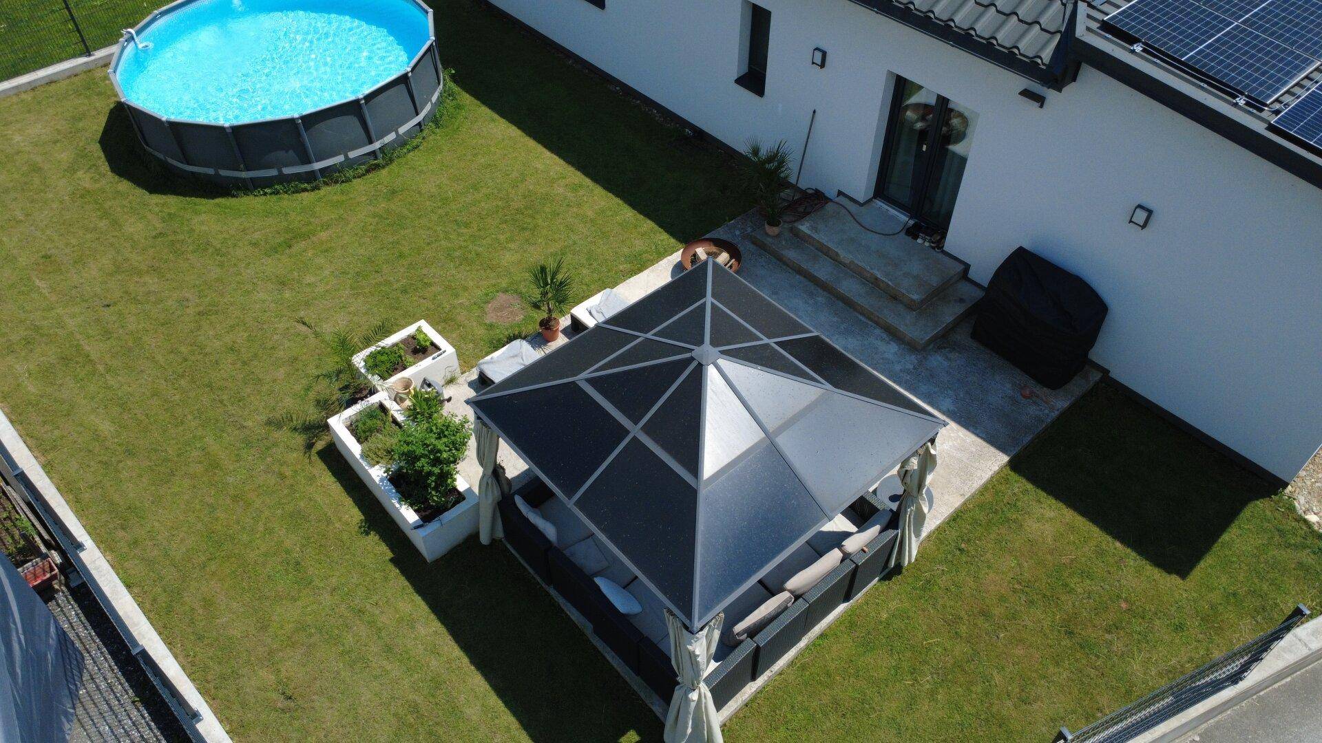 Gartenbereich mit großem Aufstellpool und einem modernen Pavillon mit Sitzgelegenheiten.