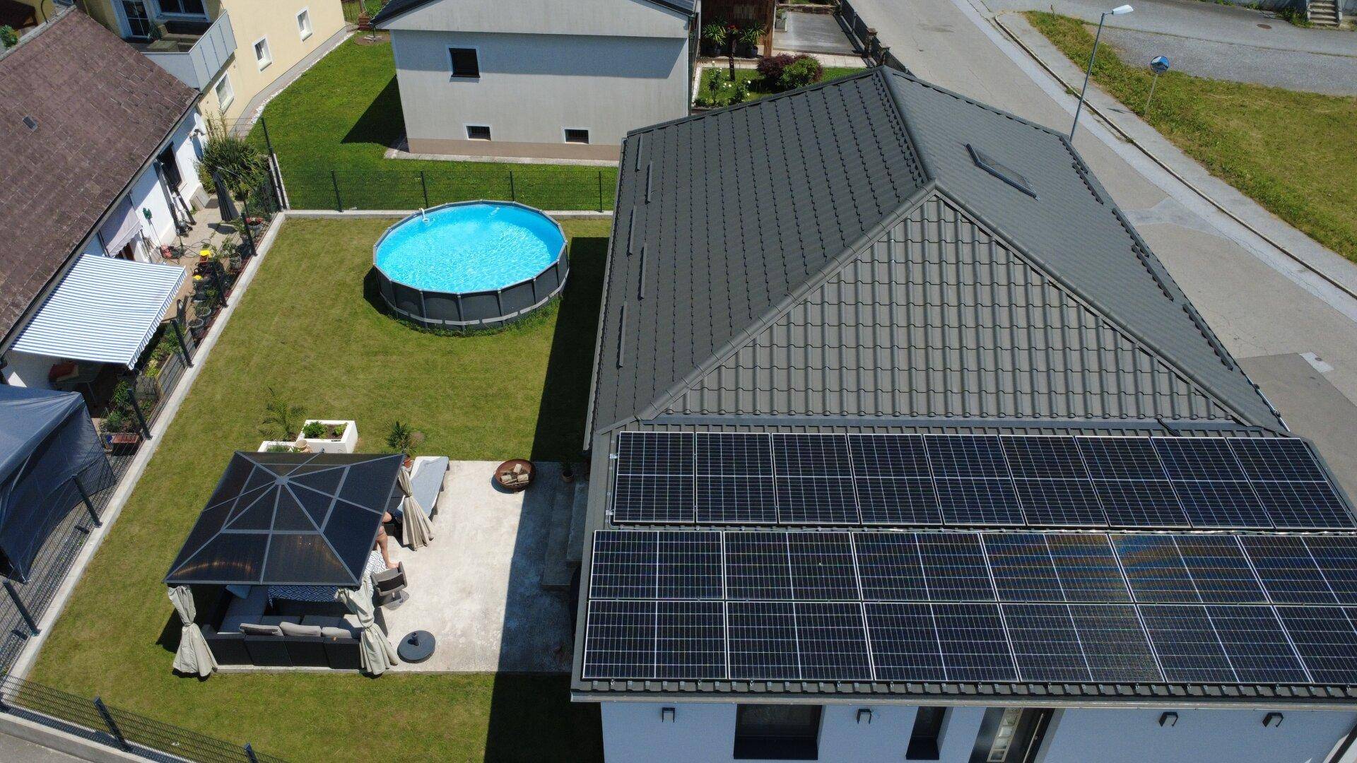 Übersicht des Hauses mit gepflegtem Garten, Pool und umfangreichen Solaranlagen auf dem Dach.