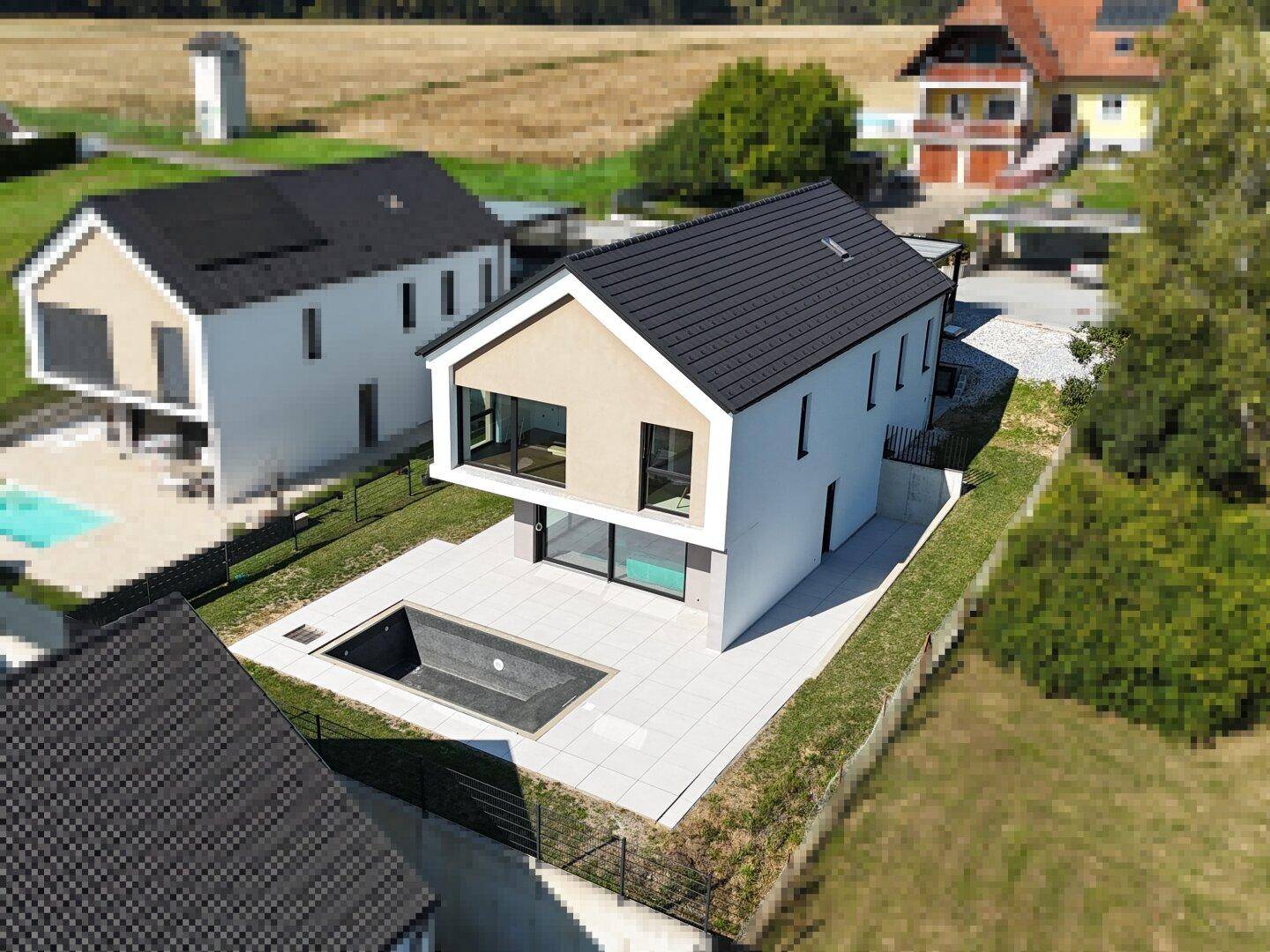 Moderne Villa mit Pool und Garten, umgeben von ländlicher Landschaft.