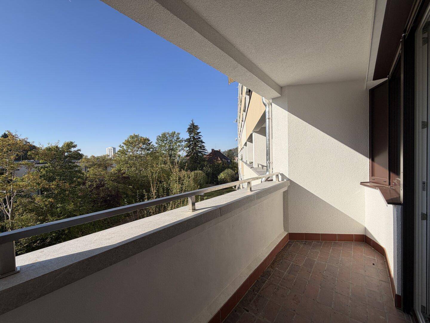 Geräumiger Balkon mit Fliesenboden und einer Brüstung, die einen schönen Ausblick bietet.
