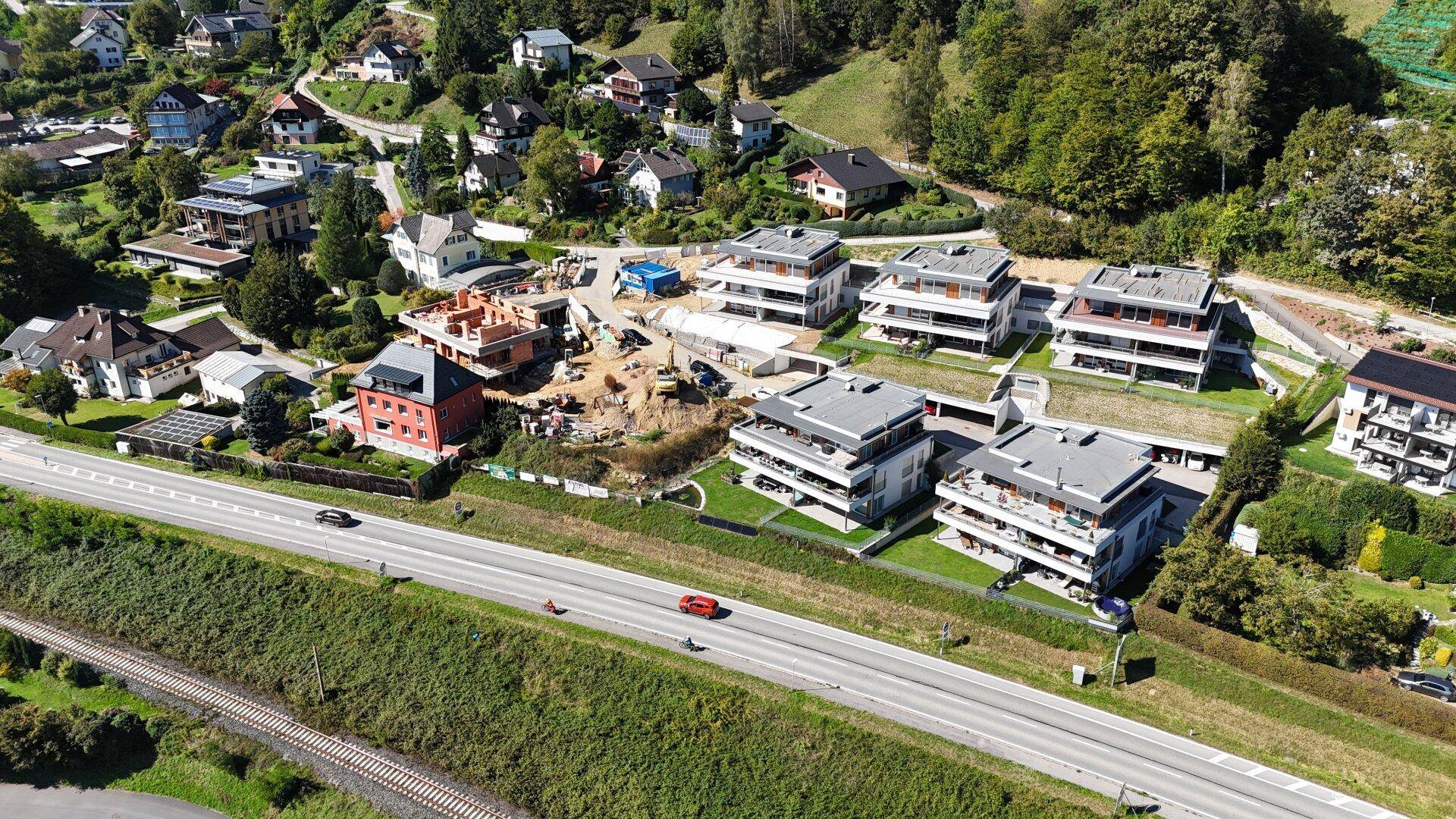 Luftaufnahme einer Baustelle mit neuen Wohngebäuden und umliegender Infrastruktur.