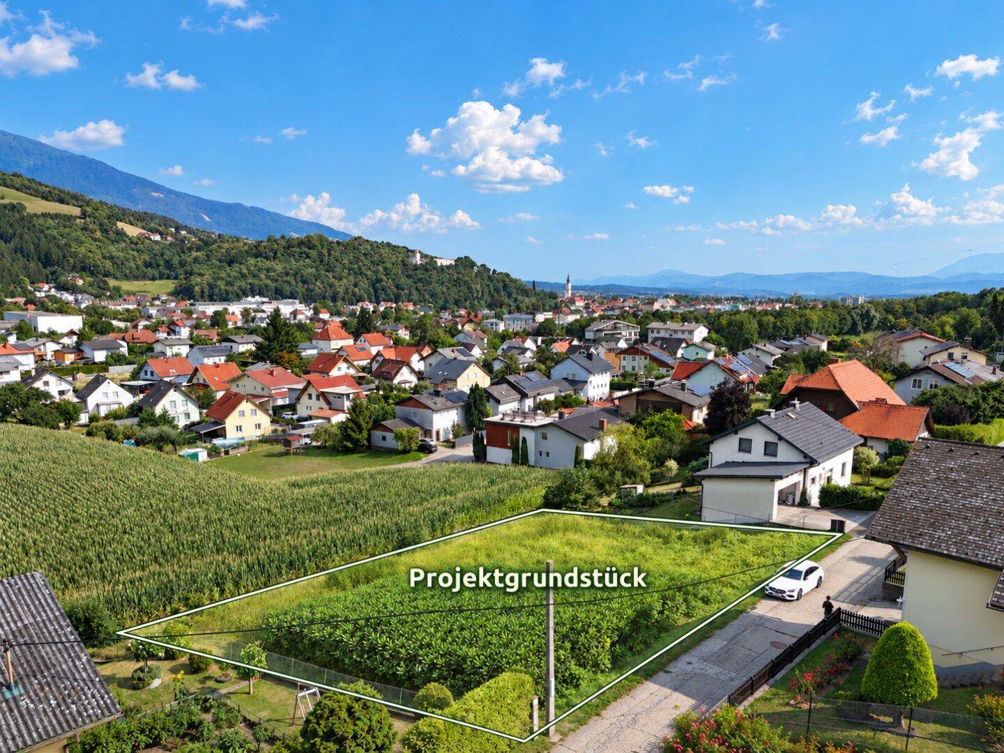 Luftaufnahme eines Projektgrundstücks in ländlicher Umgebung mit Bergblick.