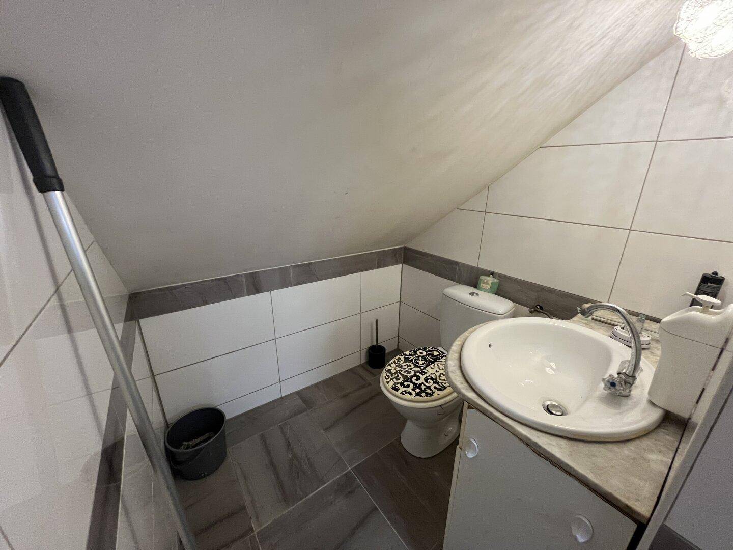 Kleines Gäste-WC im Dachgeschoss mit schrägen Wänden, Fliesenboden und modernem Waschbecken.