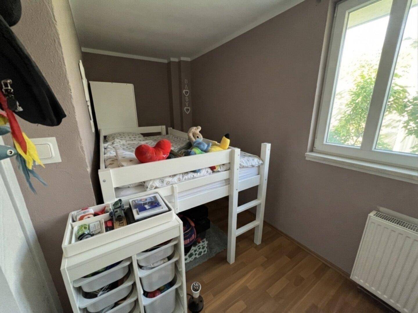 Kinderzimmer mit Hochbett, Spielzeug und hellem Fenster für natürliches Licht.