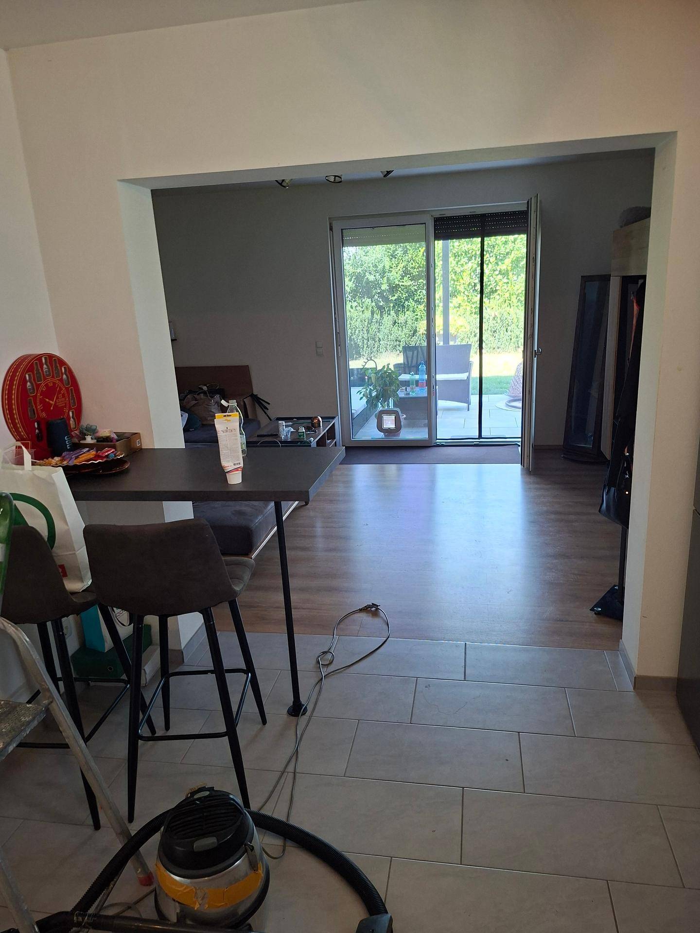 Offener Wohn- und Essbereich mit Bartisch, Laminatboden und Zugang zur Terrasse.