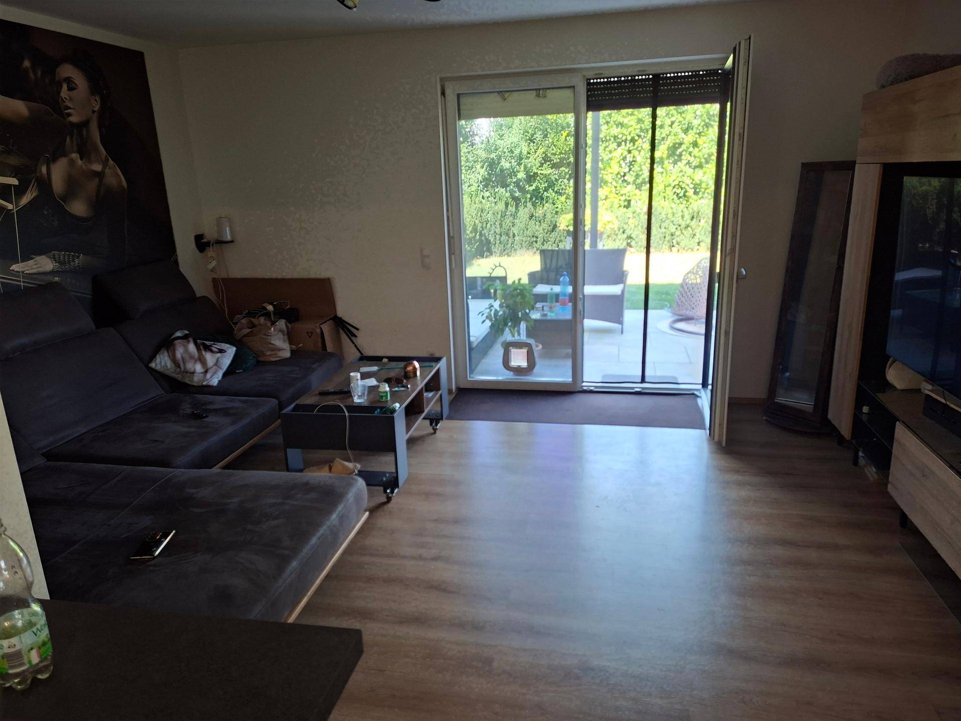 Helles Wohnzimmer mit bequemer Couch und weitem Blick in den grünen Garten.