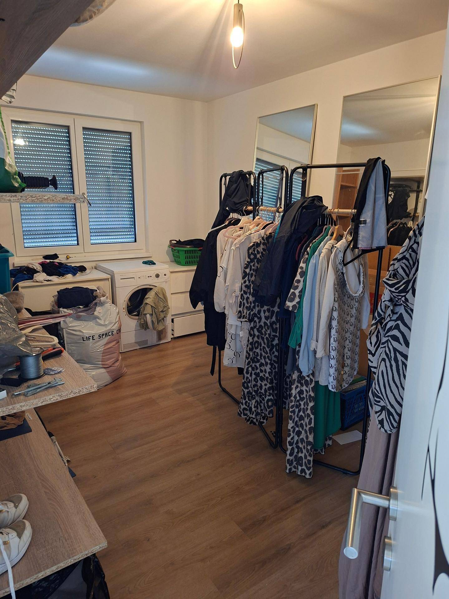 Waschküche mit Waschmaschine, Trockner und Regalen, auch als Ankleidezimmer genutzt.
