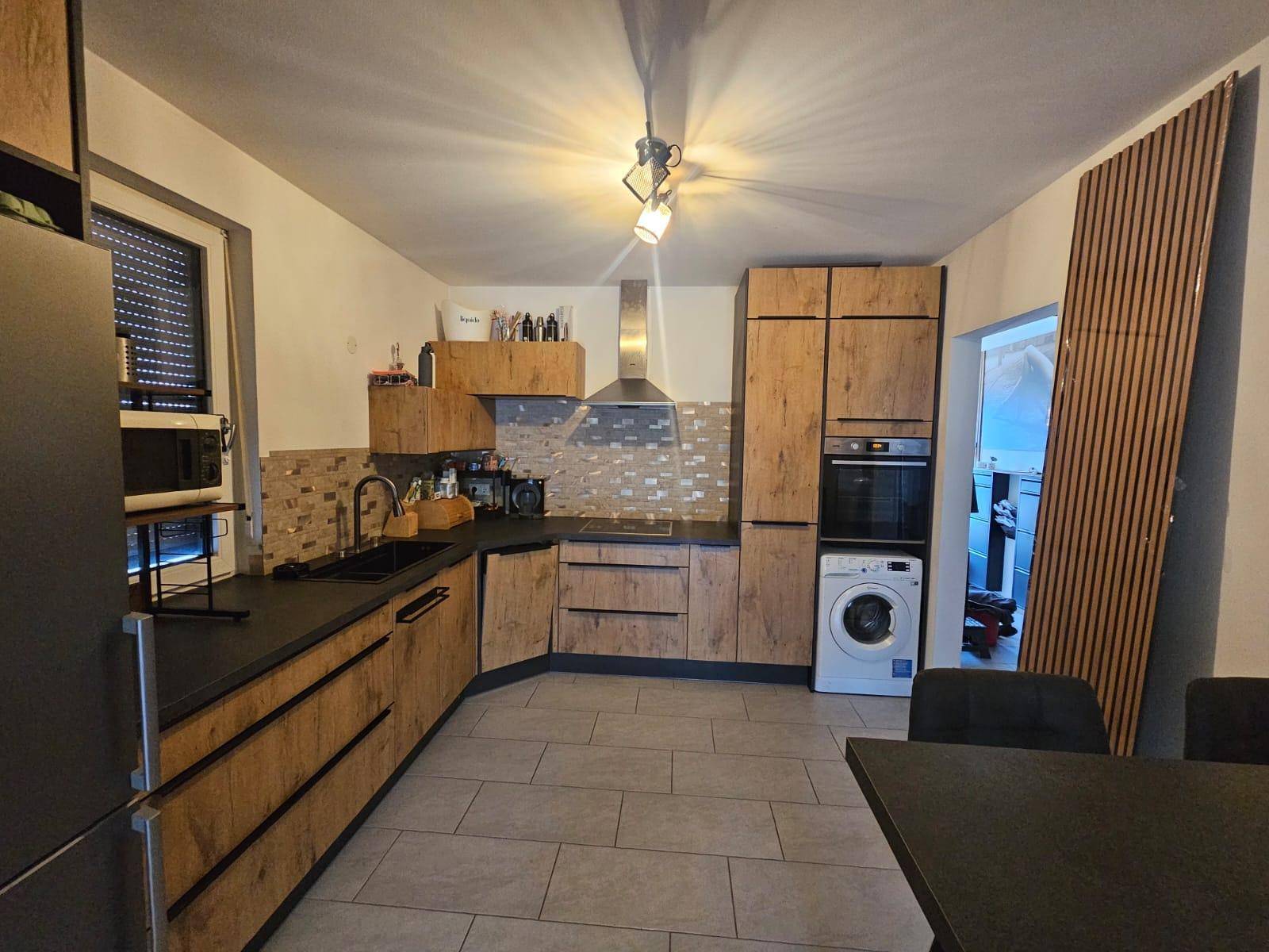 Moderne Küche mit Holzfronten, dunklen Arbeitsplatten und integrierten Geräten.