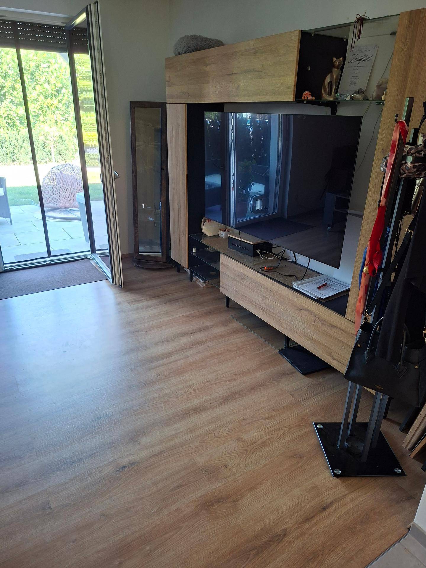 Wohnzimmer mit modernem TV-Möbel, Laminatboden und Blick auf den Garten.