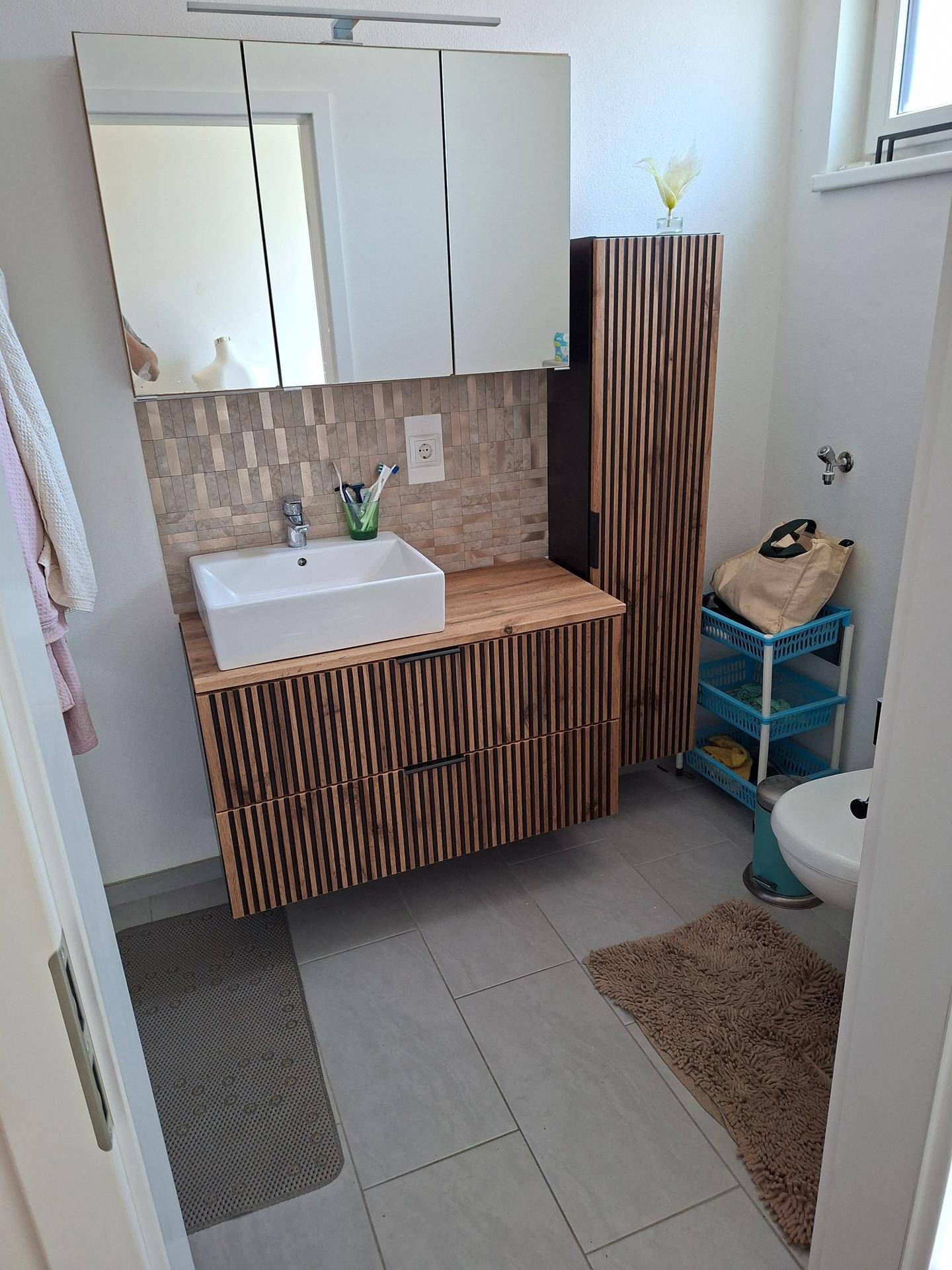 Modernes Badezimmer mit Holzwaschtisch, Aufsatzwaschbecken und Spiegelschrank.